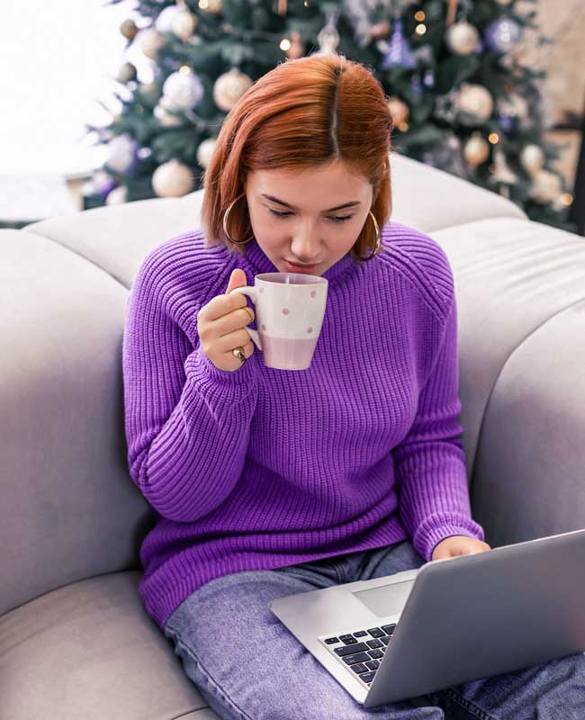 woman on laptop purple woman wearing a purple sweater using a laptop
